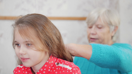 Granny enjoys combing hair to baby on sunny morning. Good time at home.の写真素材