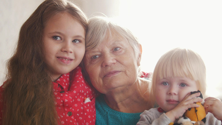 A nice girls and their grandmother enjoy sunny morning. Good time at home.