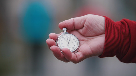 An old woman is holding an old round pocket watch.