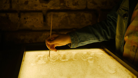 Drawing with a sand on the screen with a stick