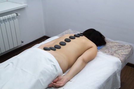 Closeup on young woman receiving hot stone massageの写真素材