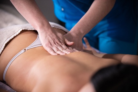Massage session. A woman receiving a massage. Back massage. Pressing on the loinの写真素材