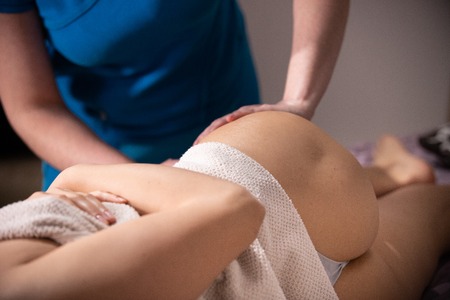 A massage session. Hips massaging. Pressing on the muscles. Close upの写真素材