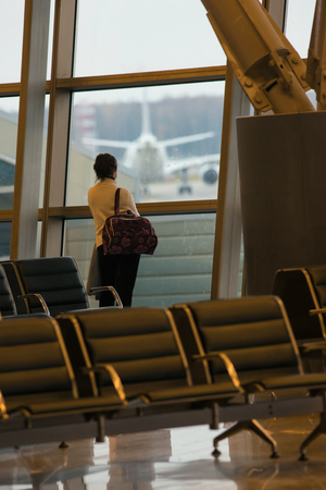 Departure lounge at the airport. A woman standing in front of the window and looking into the distanceの写真素材