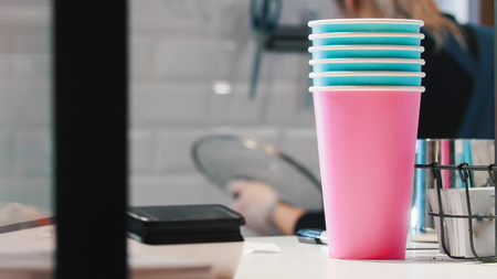 A woman making coffee. Colorful cups on the foreground.の写真素材