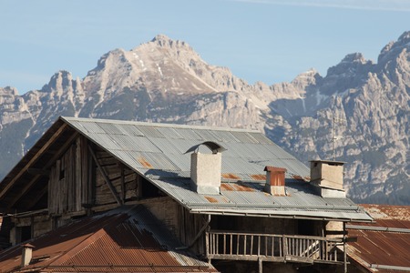 Dolomites. A village house on the background of snowy mountainsの写真素材