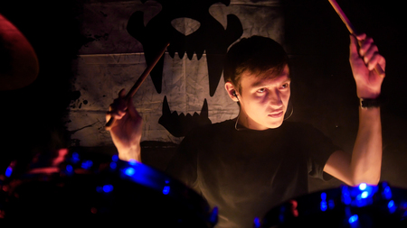 Rock concert. A man playing drums on stage. The drummer holding drumsticks.