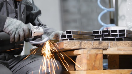 Industrial manufacturing. A man working with an iron detail. Sanding process