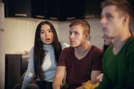Company of young friends sitting in the living room and spending time together. A funny face expressionの写真素材