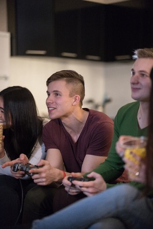 Company of young friends spending time together. Two young men playing games
