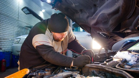 Car service. Mechanic man checks the voltageの写真素材