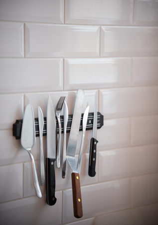 Kitchen cutlery hanging on the magnetic stripe on the wall