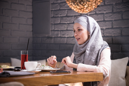 Muslim woman sitting at a table in a restaurantの写真素材