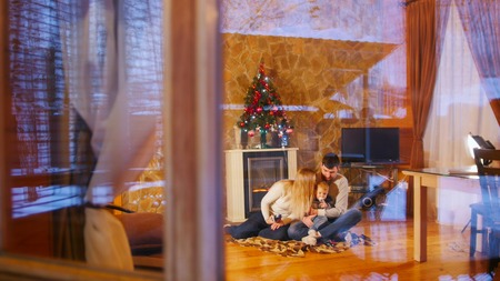 Young happy family sitting on the floor in cozy house. View from the windowの写真素材