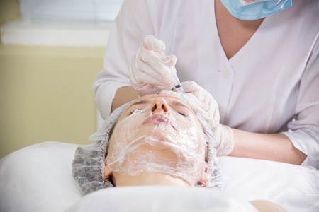 Cosmetologist working with clients face. Cosmetic procedure of mesotherapy. Doing injections in a foreheadの写真素材