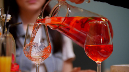 A couple sitting by table in a cafe. A man pours the drink in the glassの写真素材