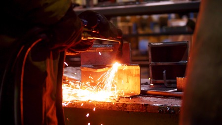 Construction plant. A man working with a welding machine. Making notches on an iron detail