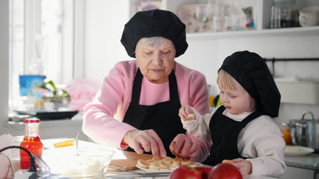 Family in the kitchen making desserts. An old woman serving a bananaの写真素材