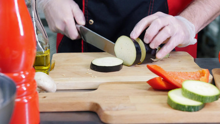 A chef working in the kitchen. Cutting the eggplantの写真素材