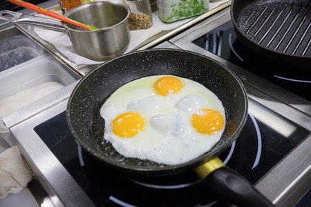 Restaurant kitchen. Chef frying eggs in the panの写真素材