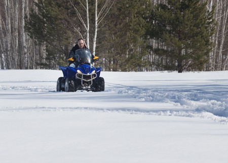 A man in winter clothes riding snowmobile in the forestの写真素材