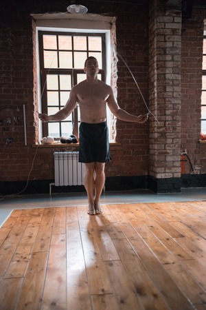 An athlete man jumping over the jump rope on training in the gymの写真素材