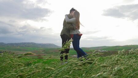 A young couple standing on the field and hug