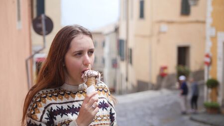 Young attractive woman eat icecream in the narrow street of the historic townの写真素材