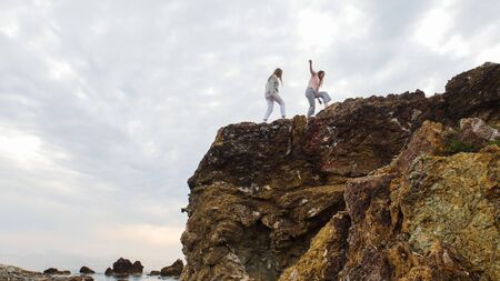 Two young women walking on massive rocks in the seafront of Pisa