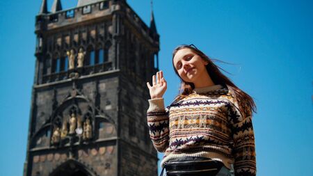 Young woman posing for photo and waving her hand on the background of the towerの写真素材