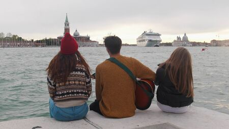 Several friends are sitting on the embankment and chatting with guitar music.
