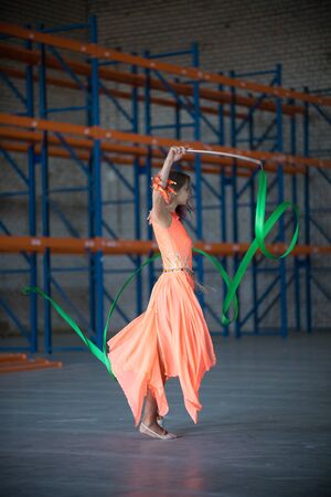 Young fit woman dancing with gymnastic ribbon in hands indoorsの写真素材