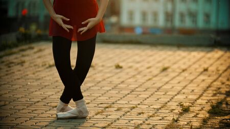 Young woman ballerina standing in the plie pose on the roof - modern buildings on the backgroundの写真素材