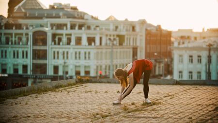 Young woman ballerina on the roof - training her stretchingの写真素材