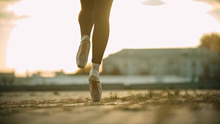 Legs of young woman ballerina running on the roof on her tiptoes - sunsetの写真素材