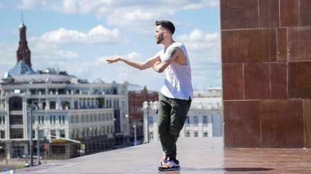 Young stylish man freestyle dancing on the stand - centre of the city on the backgroundの写真素材