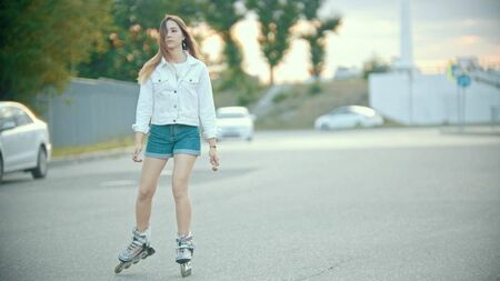 A shy teenage girl in roller skating on the roadの写真素材