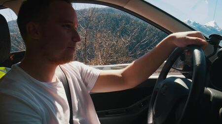 A young man riding a car - a view on mountains from the window - Dolomites