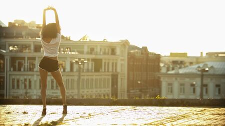 A young attractive woman on high heels standing on the roof with her hands upの写真素材