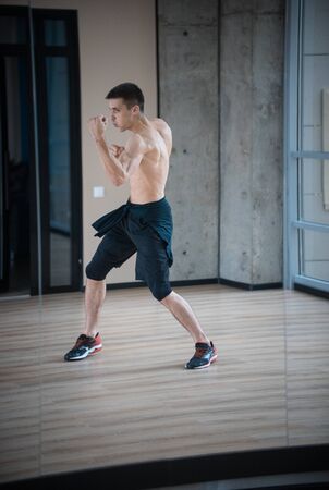 An athletic man boxer standing in fighting pose in the bright studioの写真素材