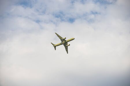 Big yellow passenger plane flying in the cloudy skies