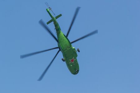 A military bright green helicopter with red star on the the bottom flying in the sky