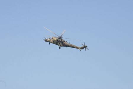 A green military helicopter flying - clear blue sky