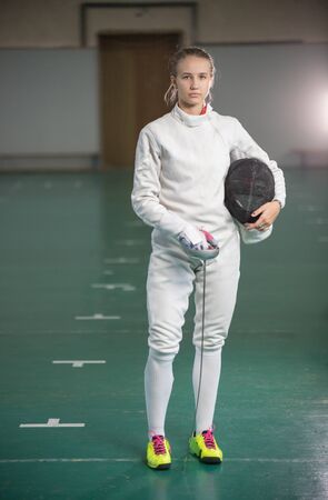 A young woman fencer standing in the gymの写真素材
