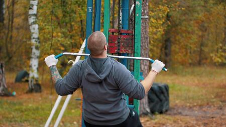 A man bodybuilder training on the outdoors sports ground - autumn forest