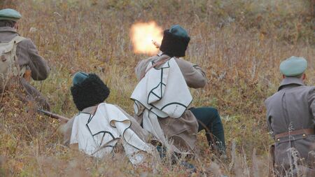 Four soldiers in the field and one of them is shooting.