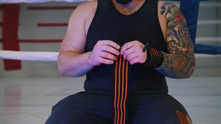 Tattooed powerlifter is straightening his elastic bandage