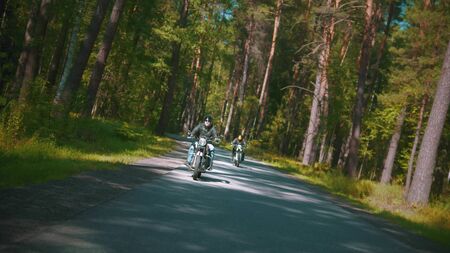 Two bikers are riding fast theis bikes on the road in the forest - outdoorsの写真素材