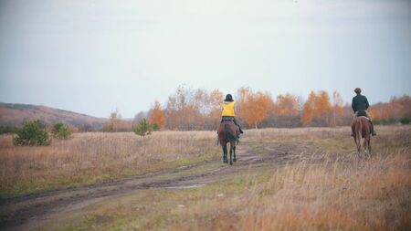 Two women are riding ginger horses on the autumn field - outdoorsの写真素材