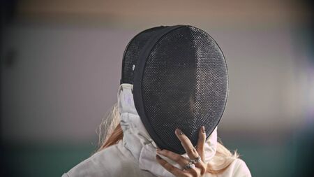 Fencer is putting a helmet on her headの写真素材